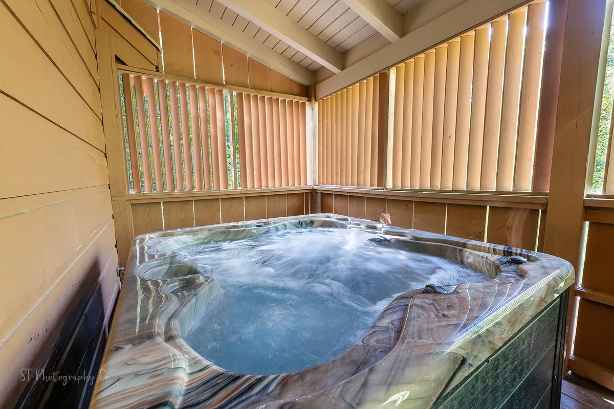 An inviting indoor hot tub set against wooden blinds and smooth stone surfaces. The intimate setting suggests soothing soaks, relaxation, and shared moments, with space to unwind after exploring Pigeon Forge.