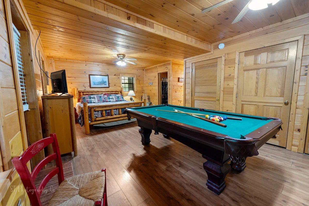 The inviting interior game room, featuring a pool table, wooden furnishings, and a cozy seating area with a ceiling fan overhead. The room is set up for friendly competitions and shared laughter, ideal for unwinding after exploring local attractions.