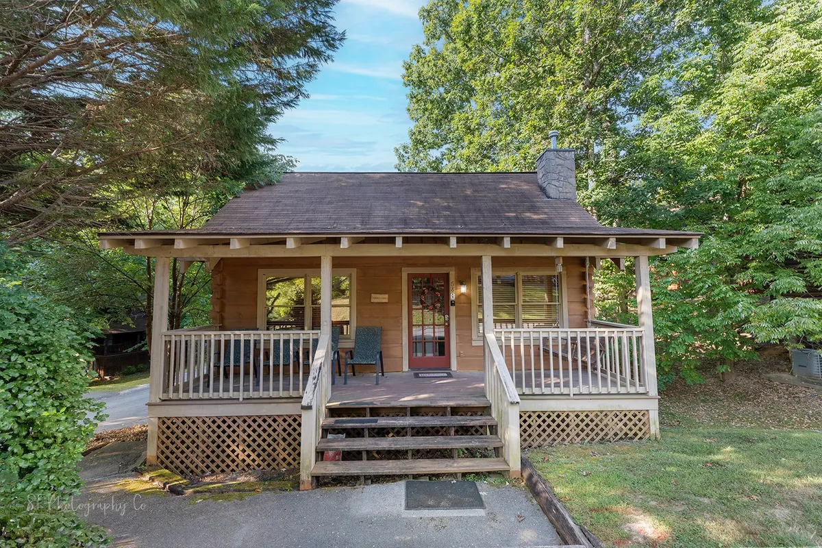 Front view of the cabin with a cozy porch, wooden steps, and abundant greenery. The inviting entryway leads directly to outdoor adventures, illustrating easy access for walks and park visits with pets.