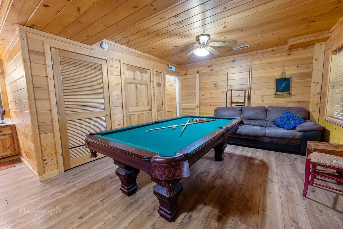 A close-up on the pool table, plush sofa, and wood-paneled walls, evoking a recreational and friendly mood ideal for gatherings and friendly competitions. The inviting textures and layout emphasize comfort and sociability.