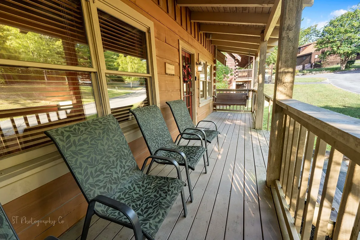 A welcoming wooden porch with comfortable chairs positioned to enjoy the outdoor view, complemented by wide windows and a homey atmosphere. The porch setting suggests relaxation and connection to the surrounding environment.